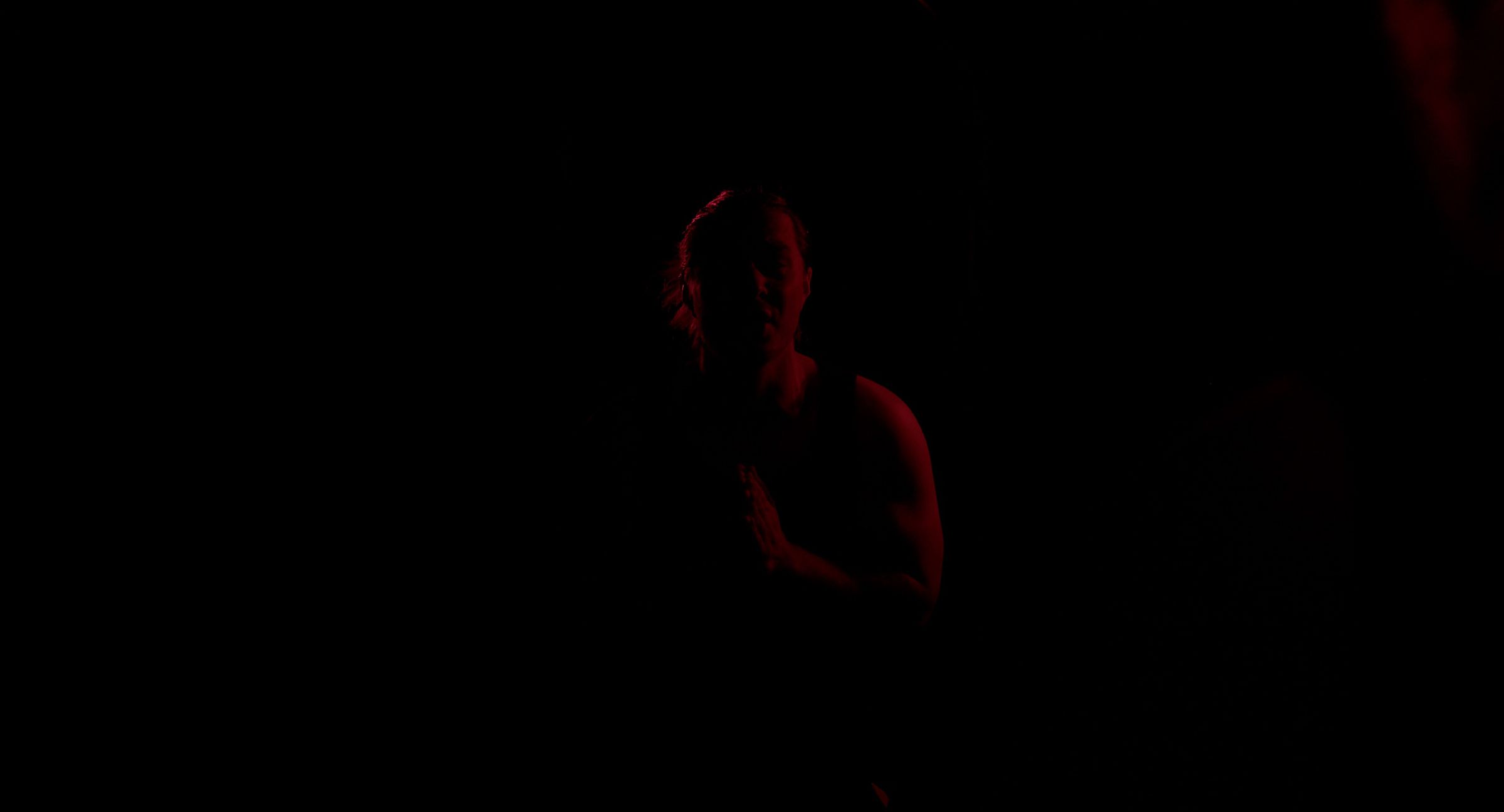 Jay Putty in dramatic red stage lighting, a still from the Worship video